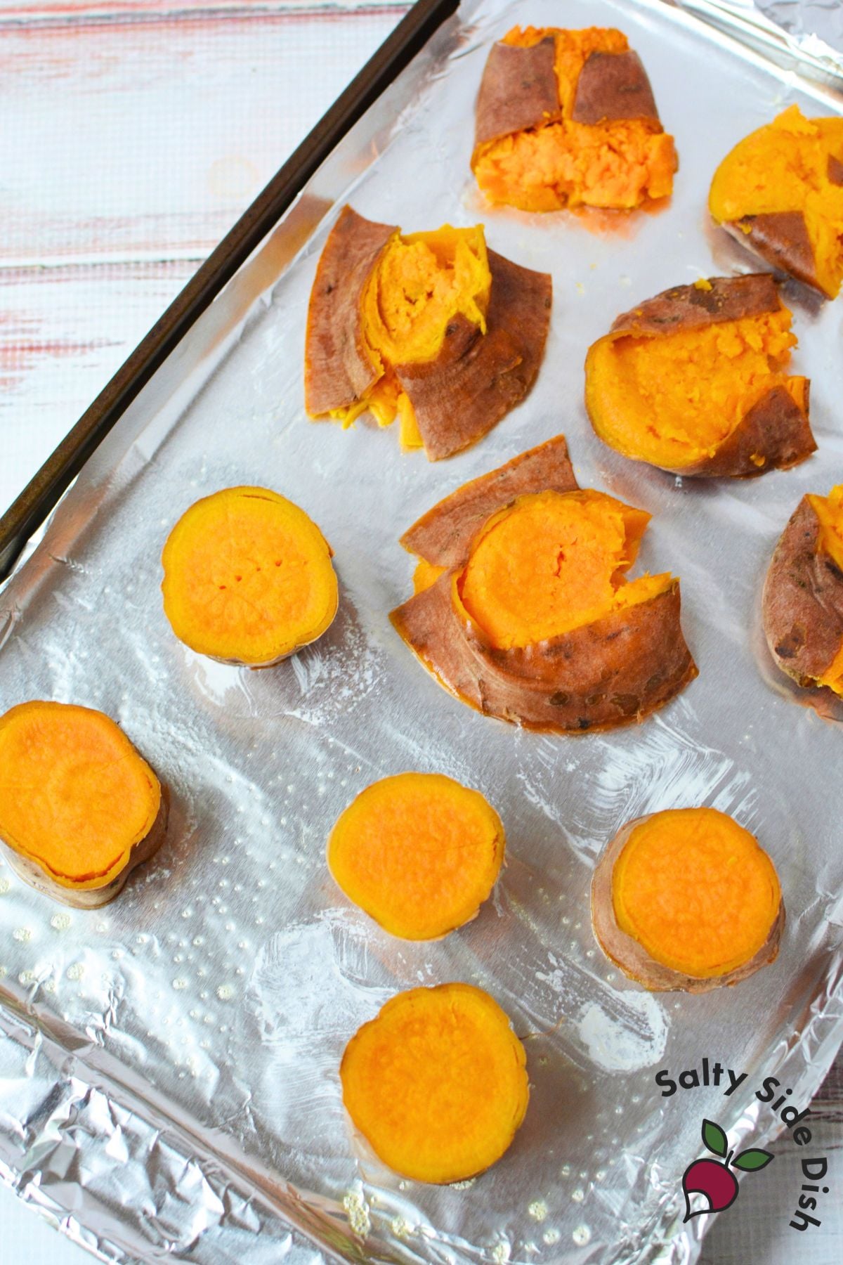 Boiled sweet potato rounds on a baking sheet before smashing and roasting