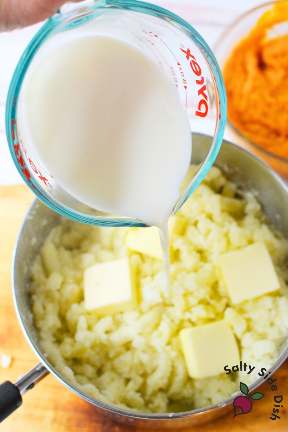 Milk and butter being added to mashed russet potatoes for pumpkin mashed potatoes