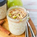 Mason jar filled with apple cinnamon overnight oats topped with diced green apple and ground cinnamon.
