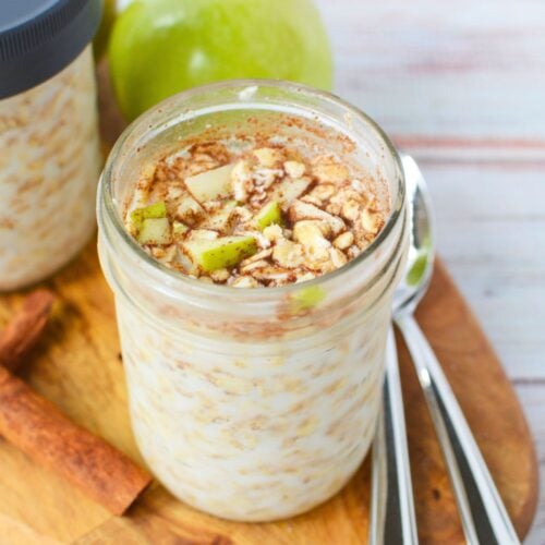 Mason jar filled with apple cinnamon overnight oats topped with diced green apple and ground cinnamon.