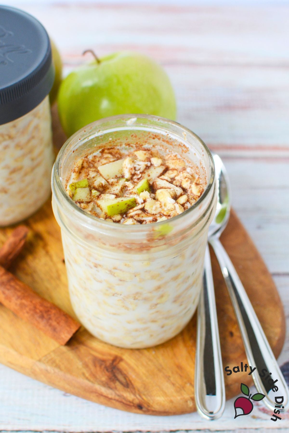 Mason jar filled with apple cinnamon overnight oats topped with diced green apple and ground cinnamon.