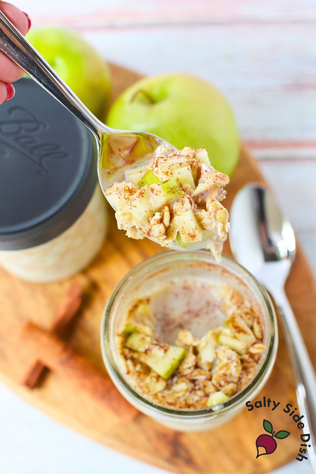 Spoonful of apple cinnamon overnight oats with diced green apple and cinnamon above a mason jar.