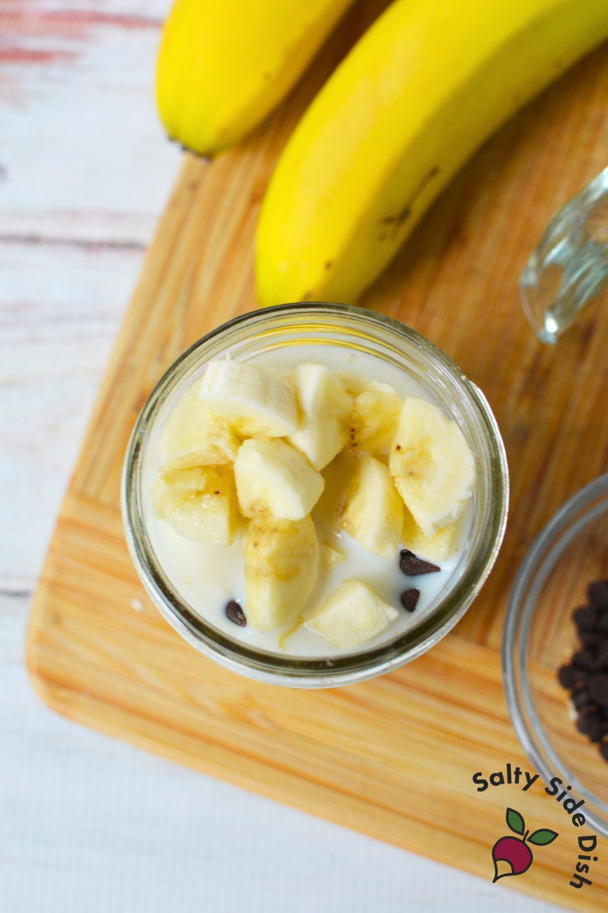 Banana chocolate overnight oats topped with sliced banana and mini chocolate chips in a mason jar.