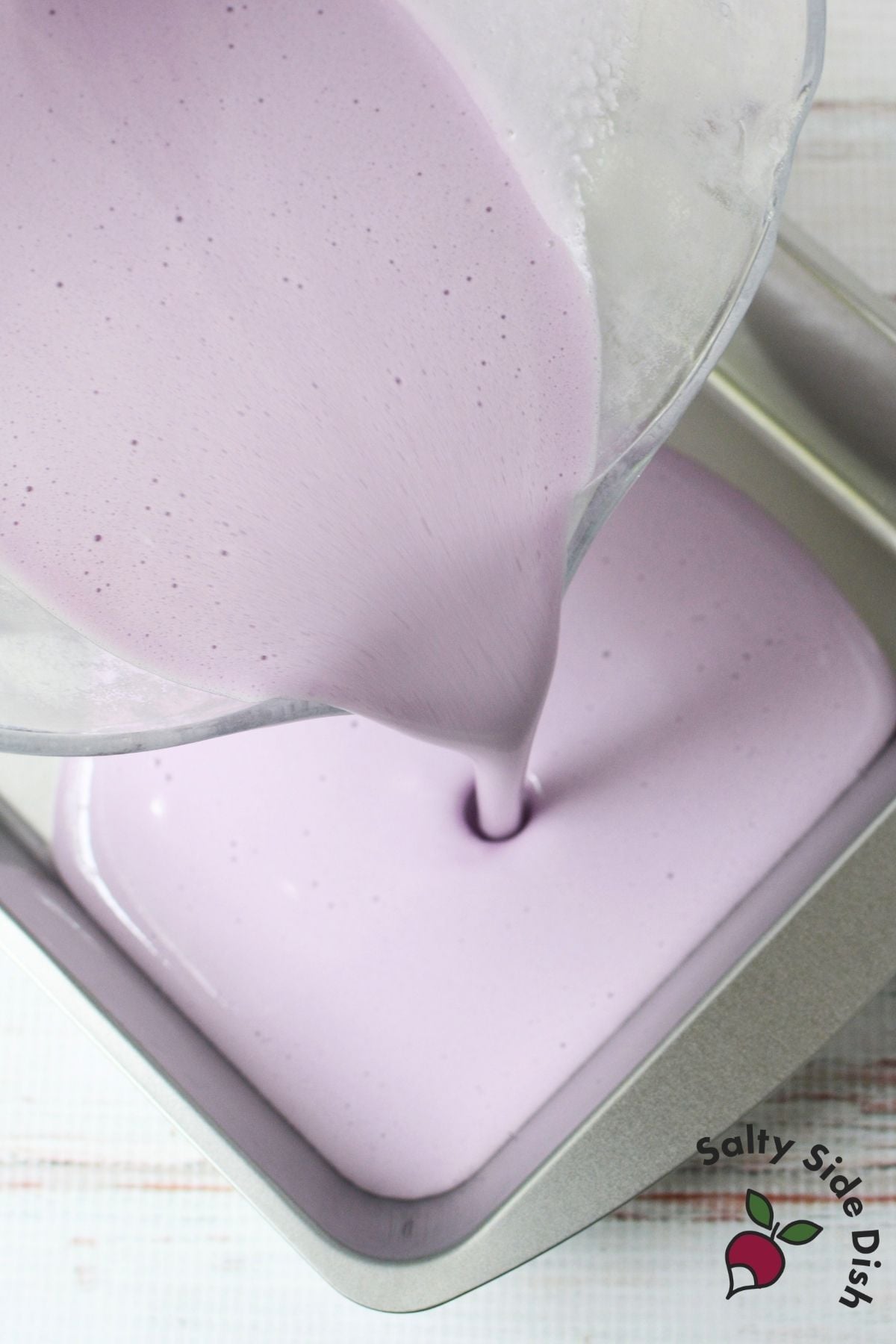 Jello marshmallow mixture being poured into an 8x8 pan to set