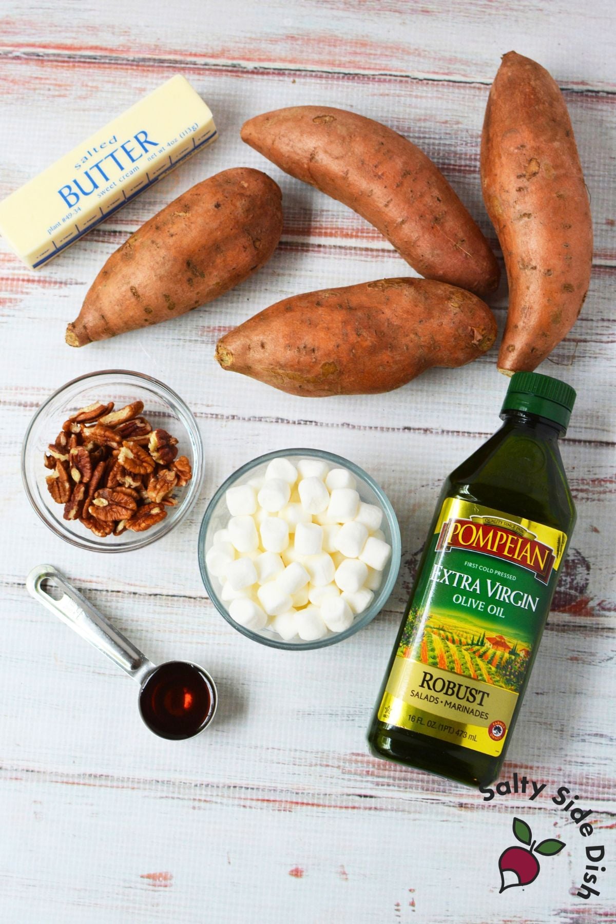Ingredients for smashed sweet potatoes including sweet potatoes, butter, olive oil, maple syrup, pecans, and marshmallows