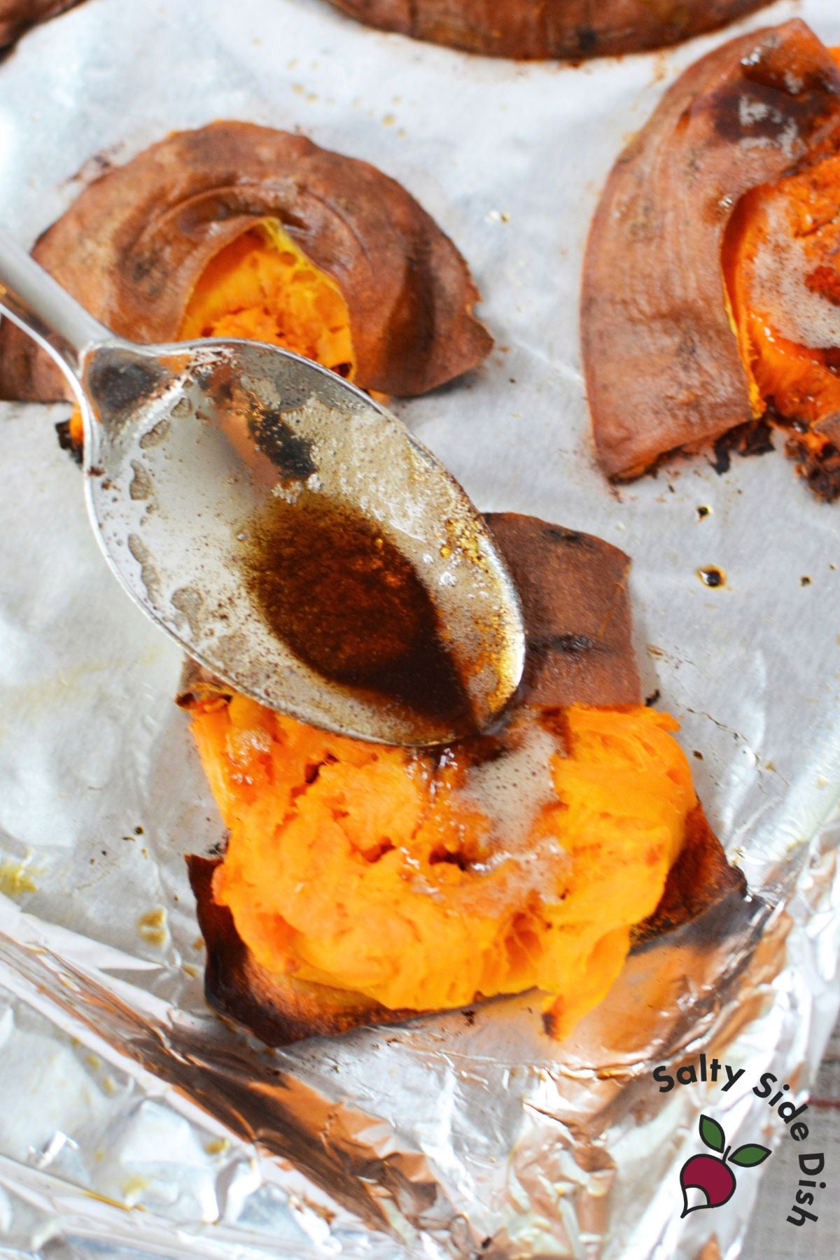 Maple brown butter being spooned over smashed sweet potatoes before adding toppings