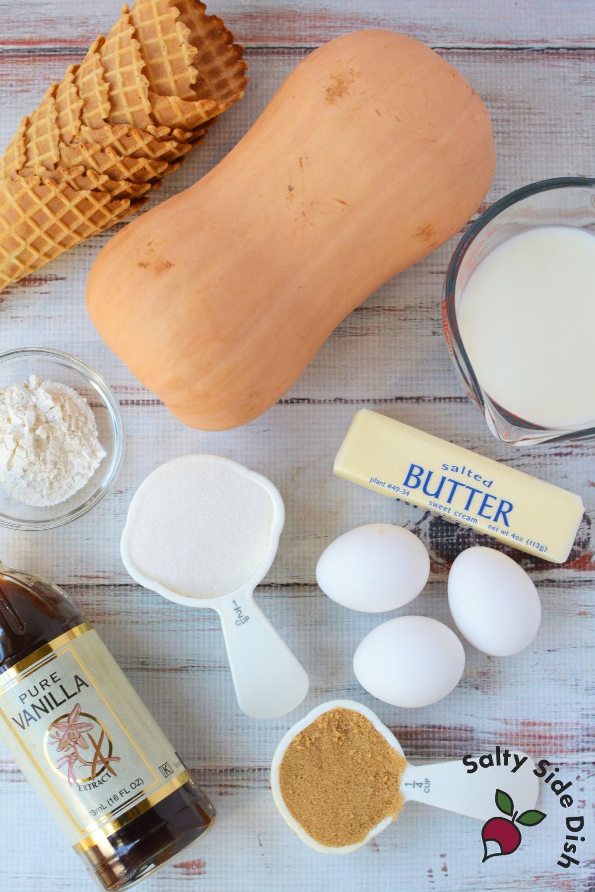 Ingredients for homemade butternut squash casserole, including fresh squash, waffle cones, butter, milk, eggs, sugar, flour, and vanilla.