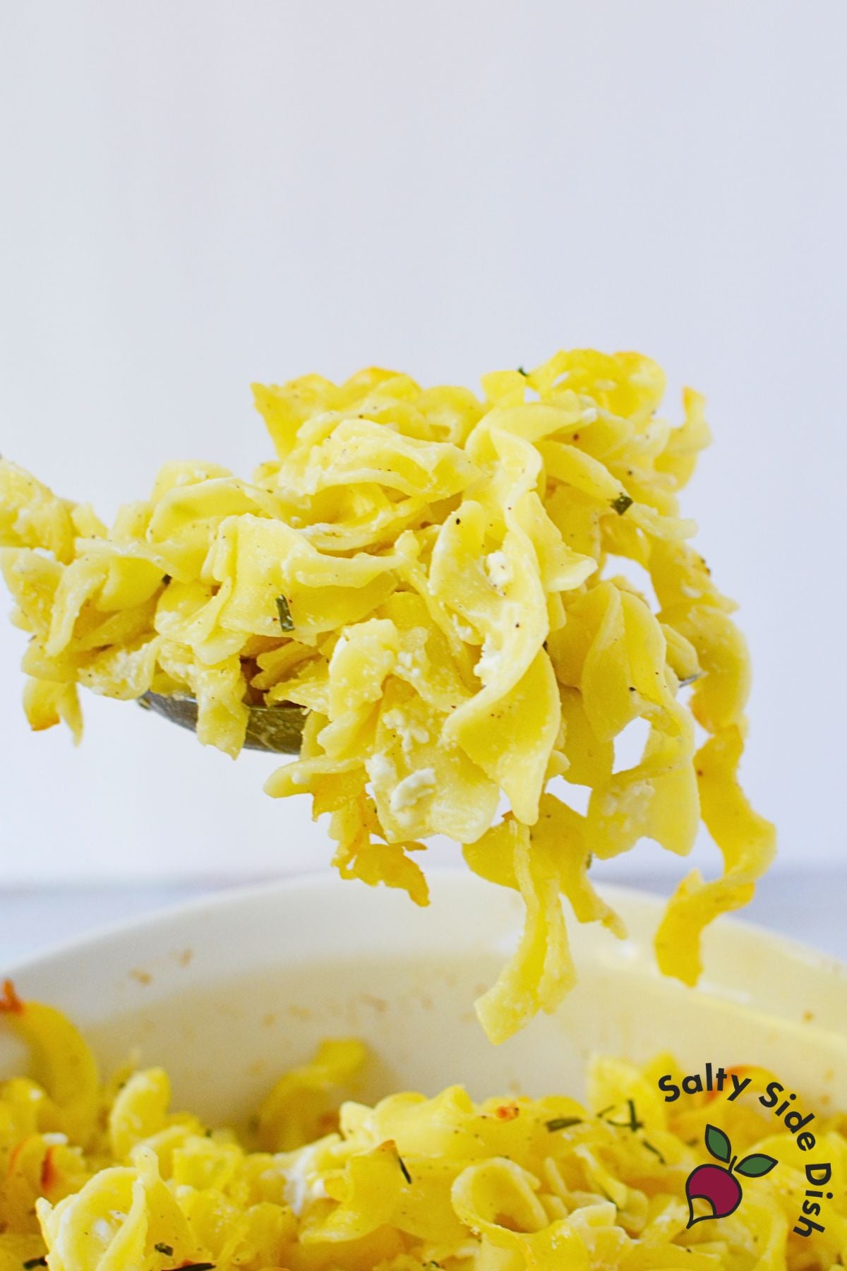 Forkful of Jackie Kennedy Casserole showing tender egg noodles coated with cottage cheese, sour cream, and fresh chives.