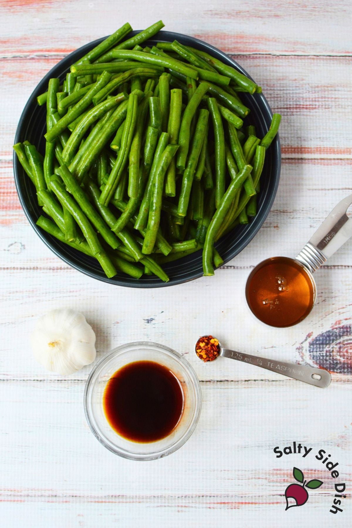 Ingredients for honey garlic green beans including fresh green beans, honey, garlic, soy sauce, and crushed red pepper flakes.