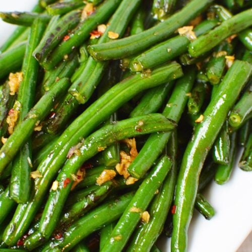 Close-up of honey garlic green beans coated with soy sauce, garlic, and red pepper flakes.