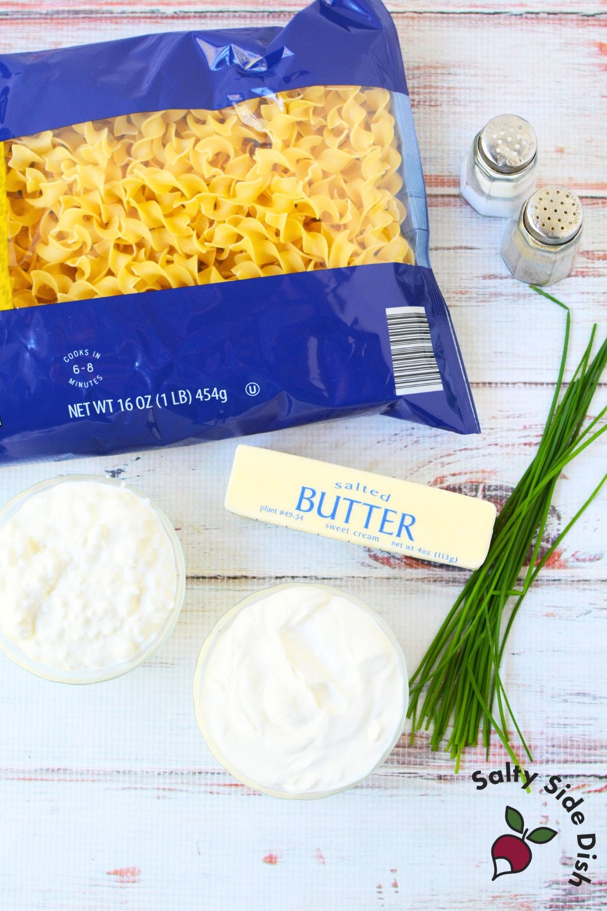 Ingredients for Jackie Kennedy Casserole including egg noodles, cottage cheese, sour cream, butter, and fresh chives.