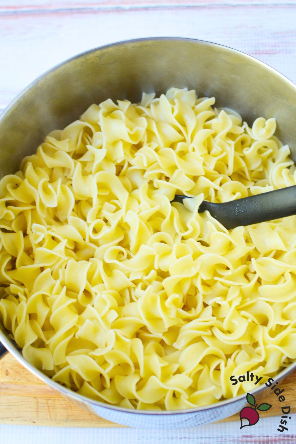 Cooked and drained egg noodles in a large pot, ready to be mixed with ingredients for Jackie Kennedy Casserole.