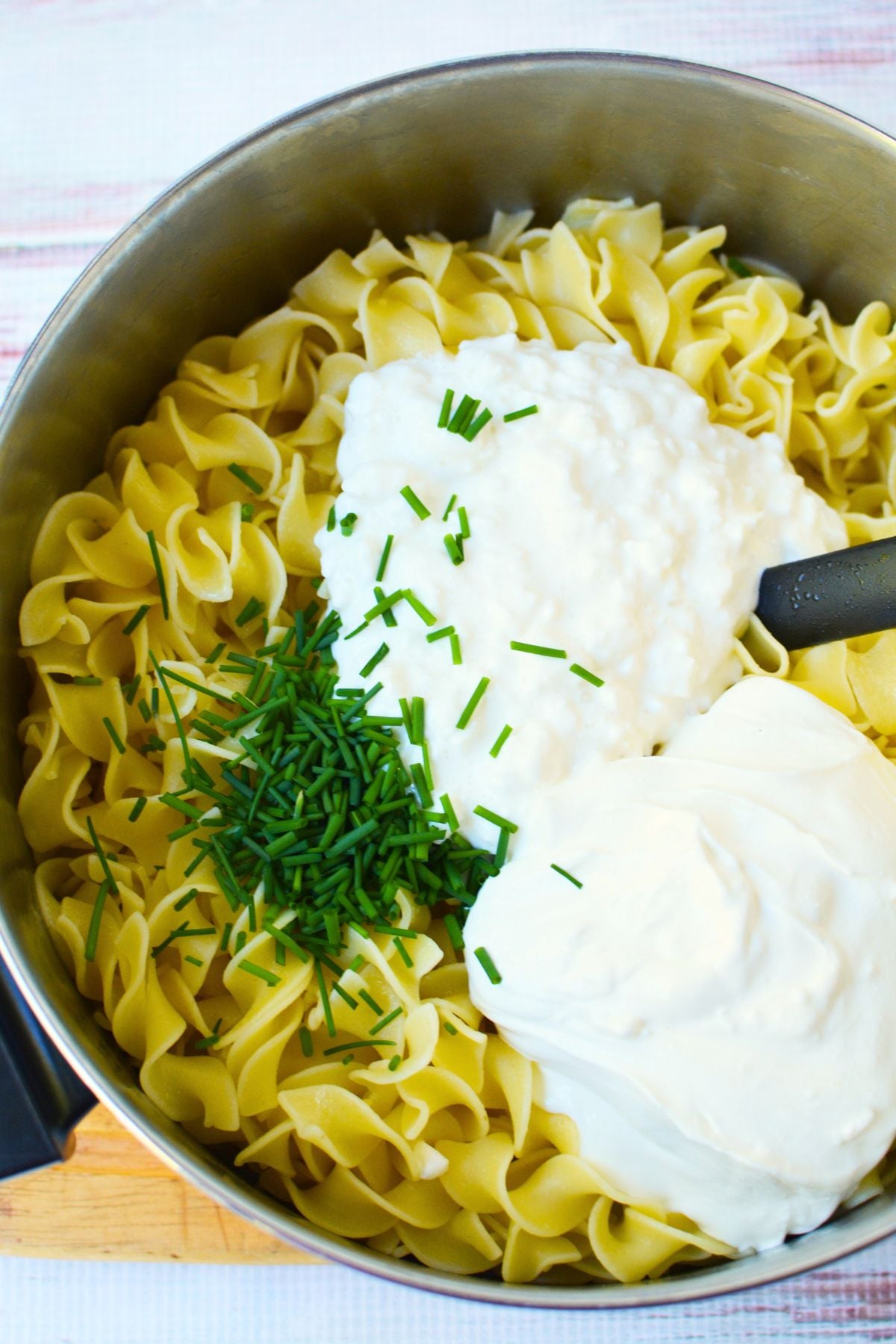 Egg noodles mixed with cottage cheese, sour cream, and chopped chives before baking into a creamy noodle side dish.
