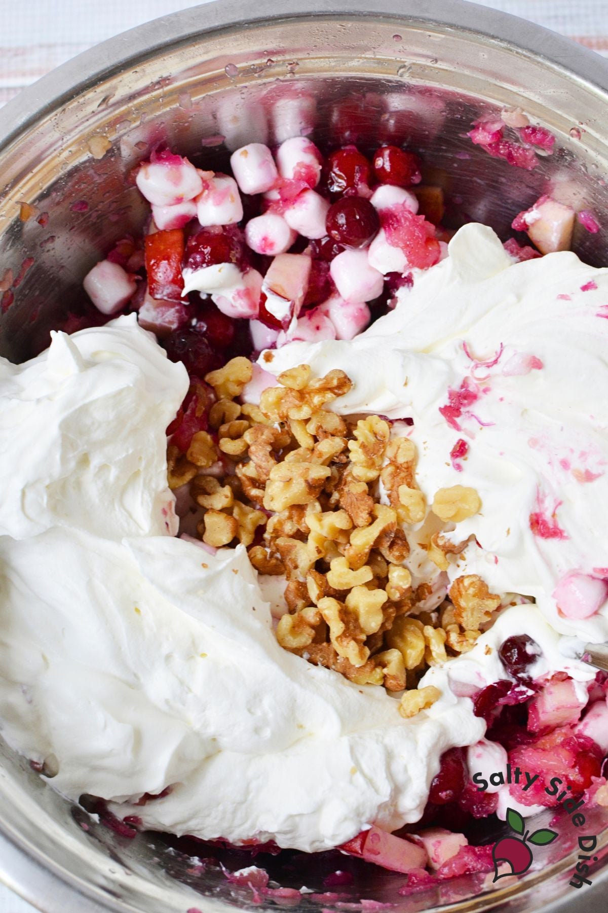 Homemade whipped cream and chopped walnuts added to cranberry salad before folding together.