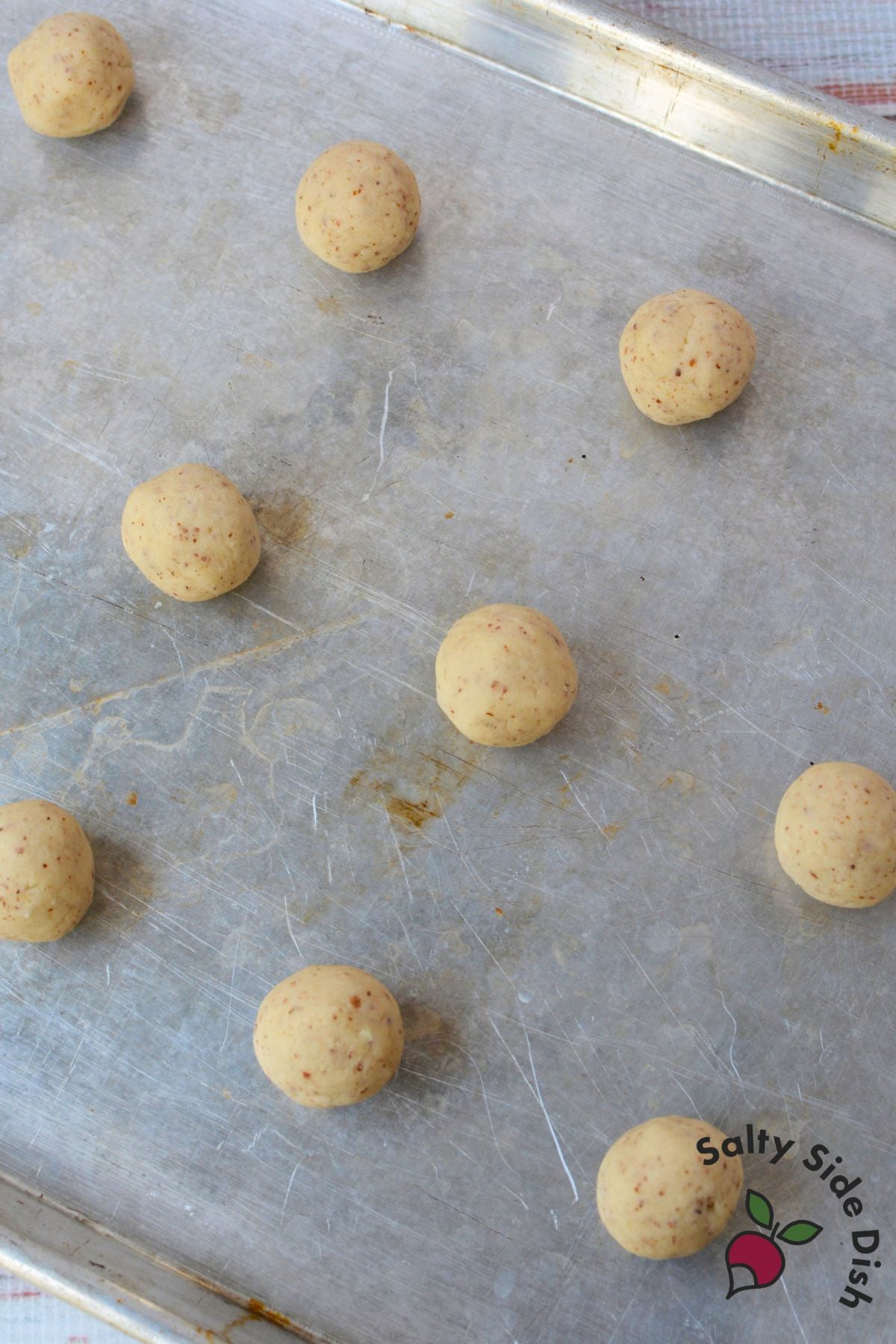 Unbaked almond snowball cookie dough rolled into balls and spaced on an ungreased metal baking sheet.