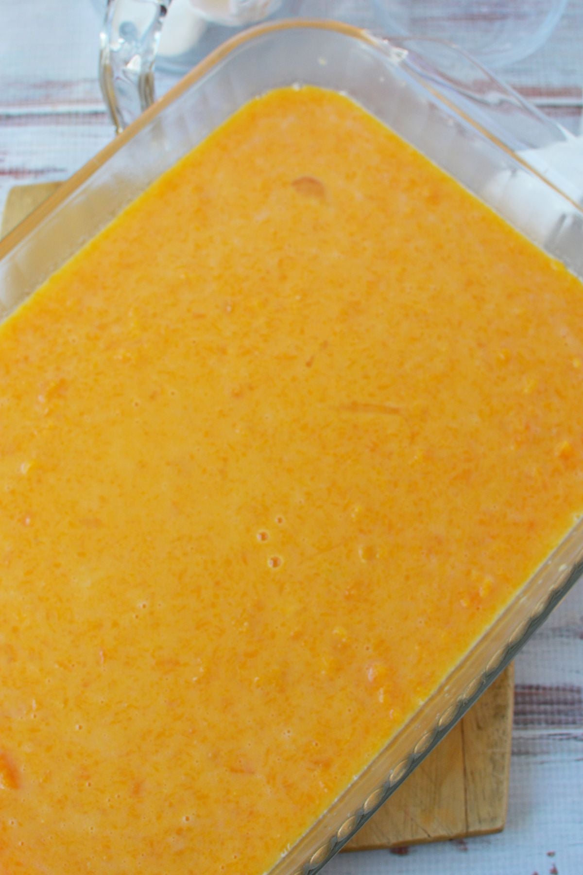 Mashed butternut squash casserole filling mixed with milk, eggs, and sugar in a glass baking dish.