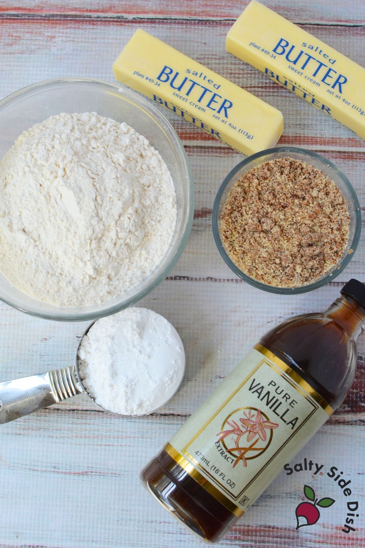 Ingredients for almond snowball cookies, including salted butter, flour, finely ground almonds, powdered sugar, and vanilla extract.