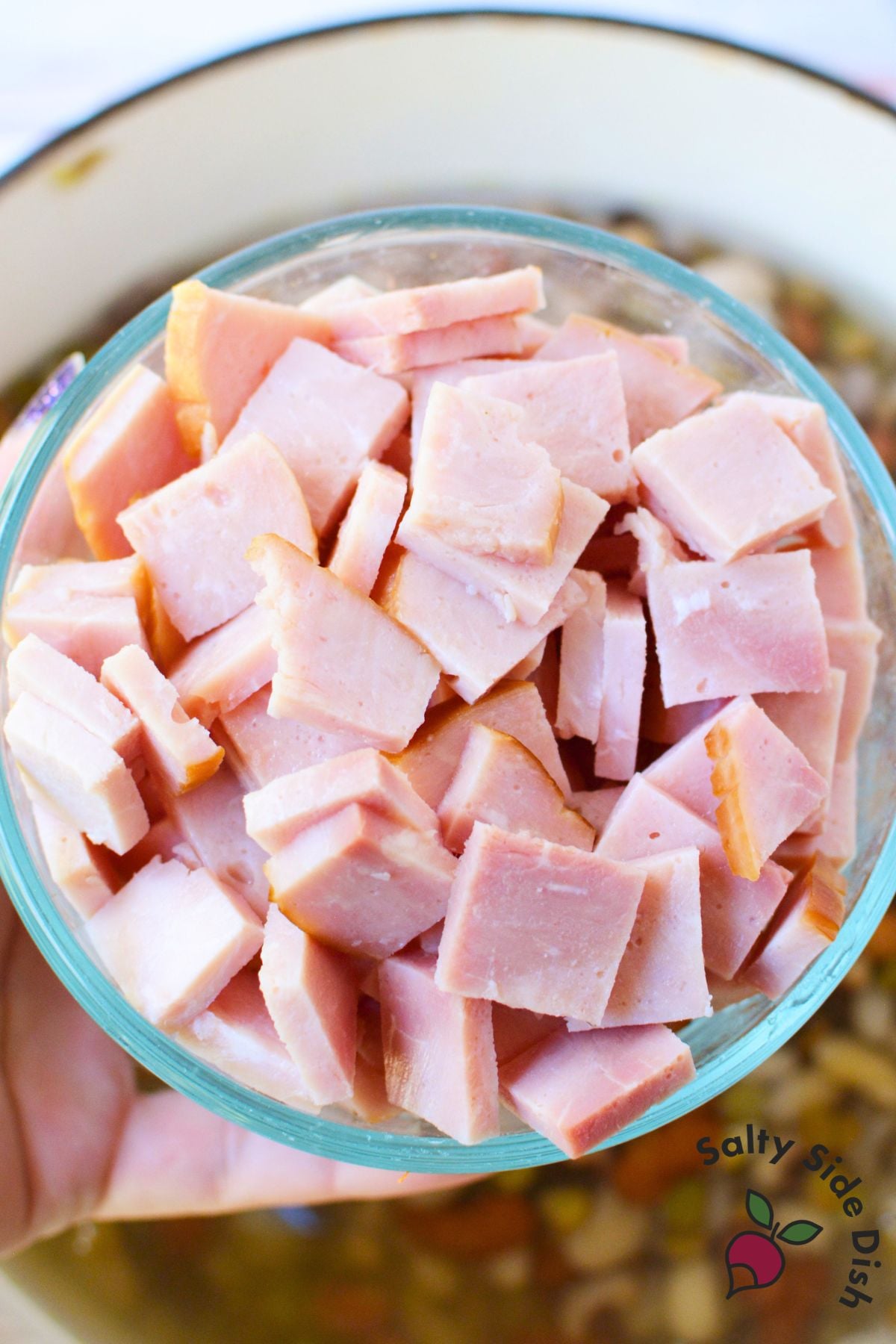 Chunks of cooked ham in a glass bowl ready to add to homemade ham and bean soup.
