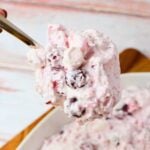 Spoonful of cranberry salad with whole cranberries, mini marshmallows, and homemade whipped cream.