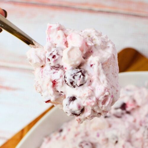 Spoonful of cranberry salad with whole cranberries, mini marshmallows, and homemade whipped cream.