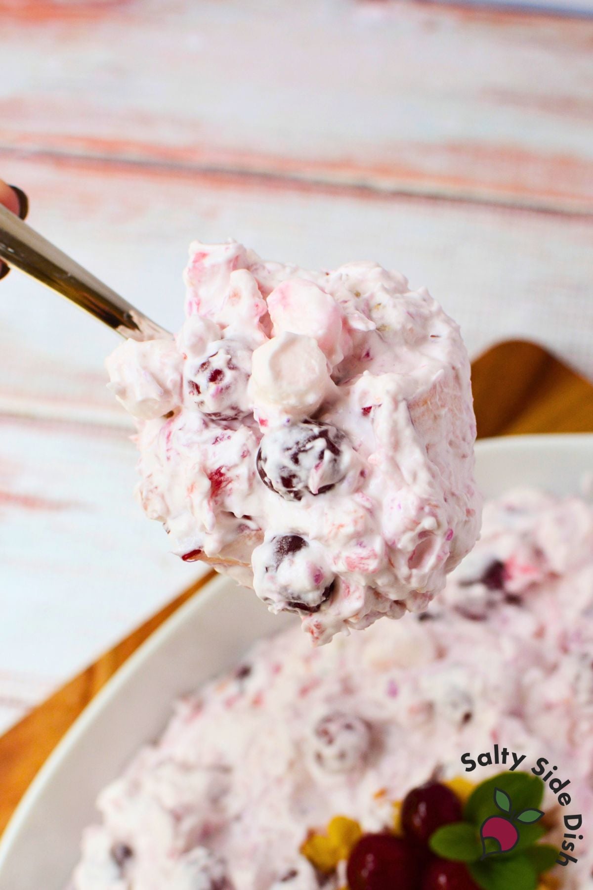 Spoonful of cranberry salad with whole cranberries, mini marshmallows, and homemade whipped cream.