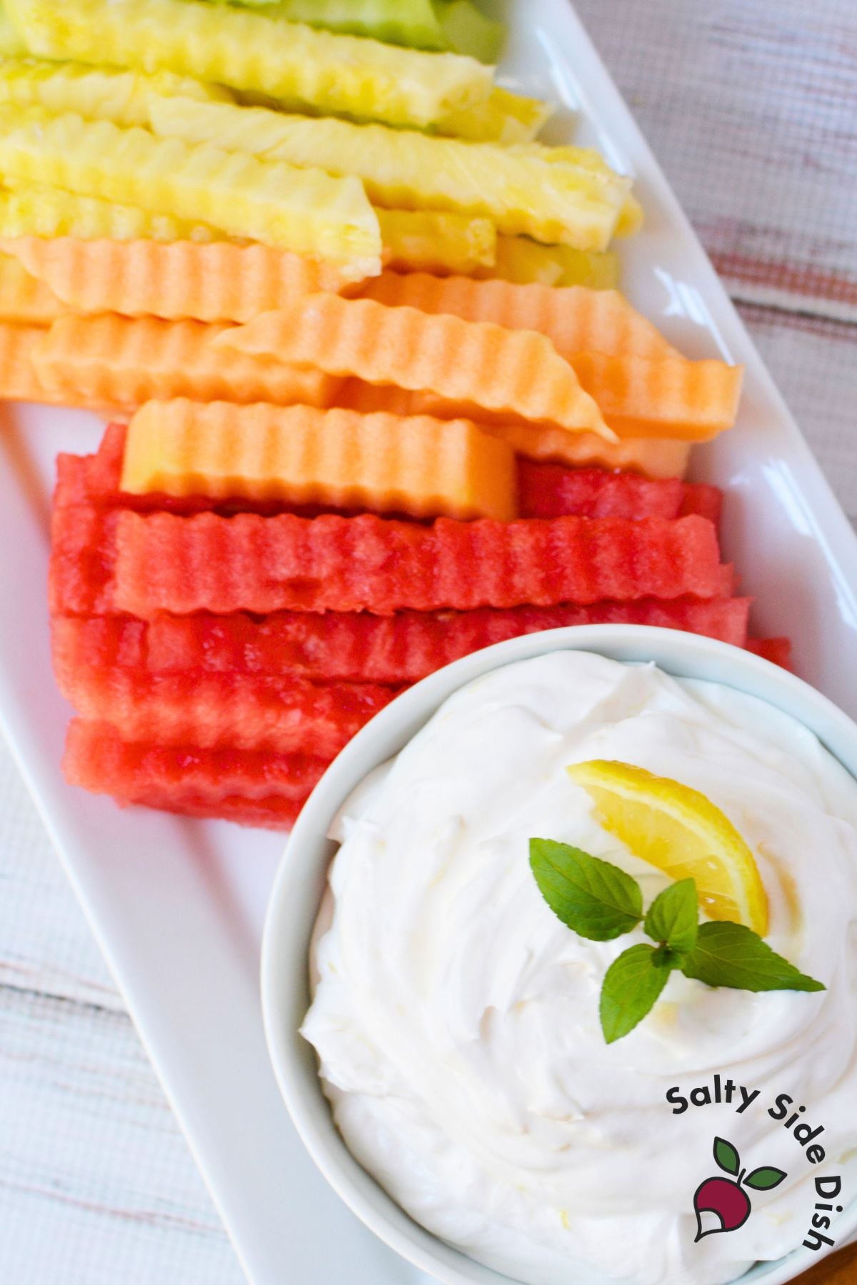 Watermelon, cantaloupe, pineapple, and honeydew fruit fries arranged on a platter with creamy lemon dip.