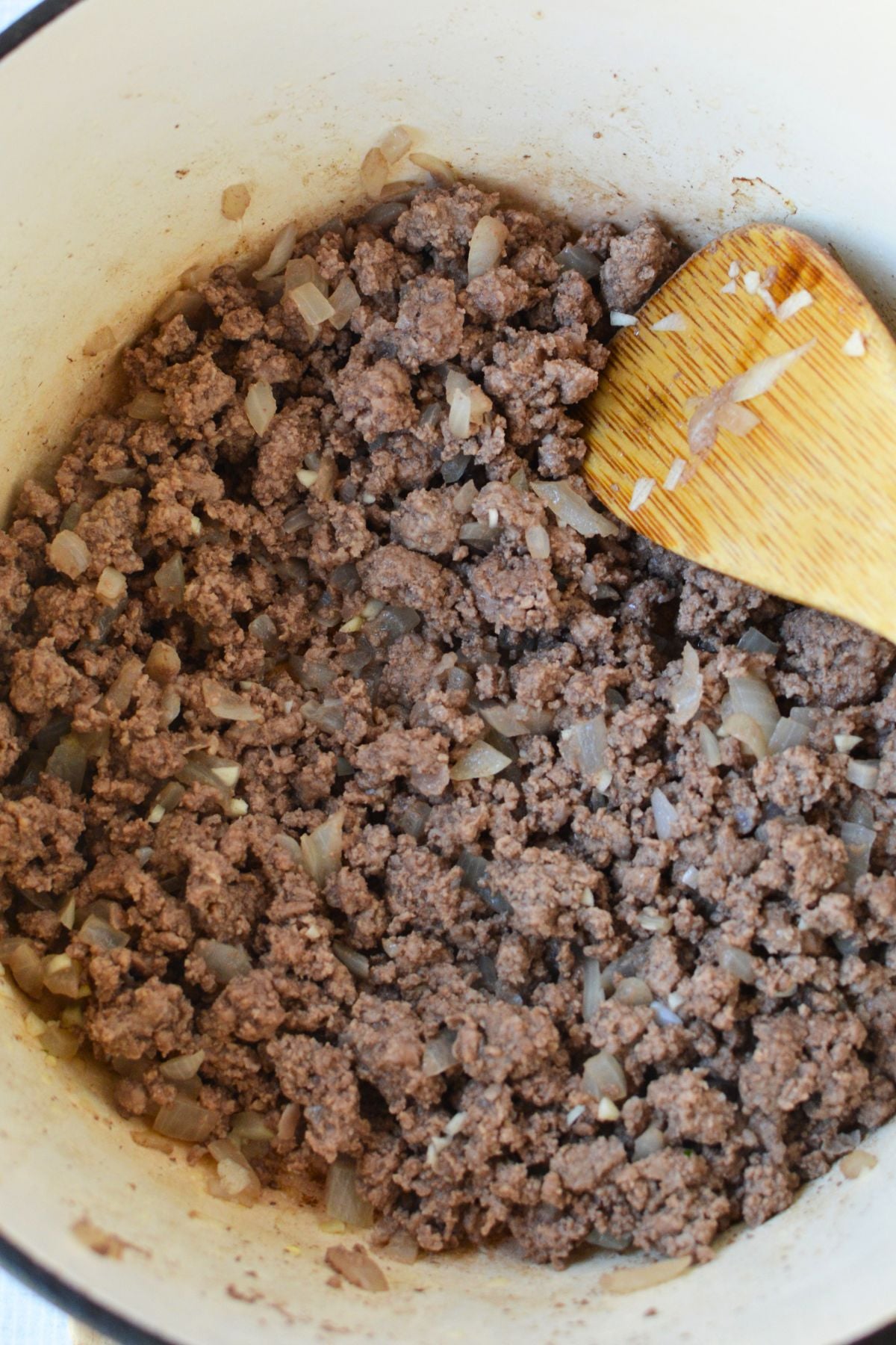 Cooked ground beef with chopped onions and garlic in a Dutch oven before adding ingredients for stuffed pepper soup.