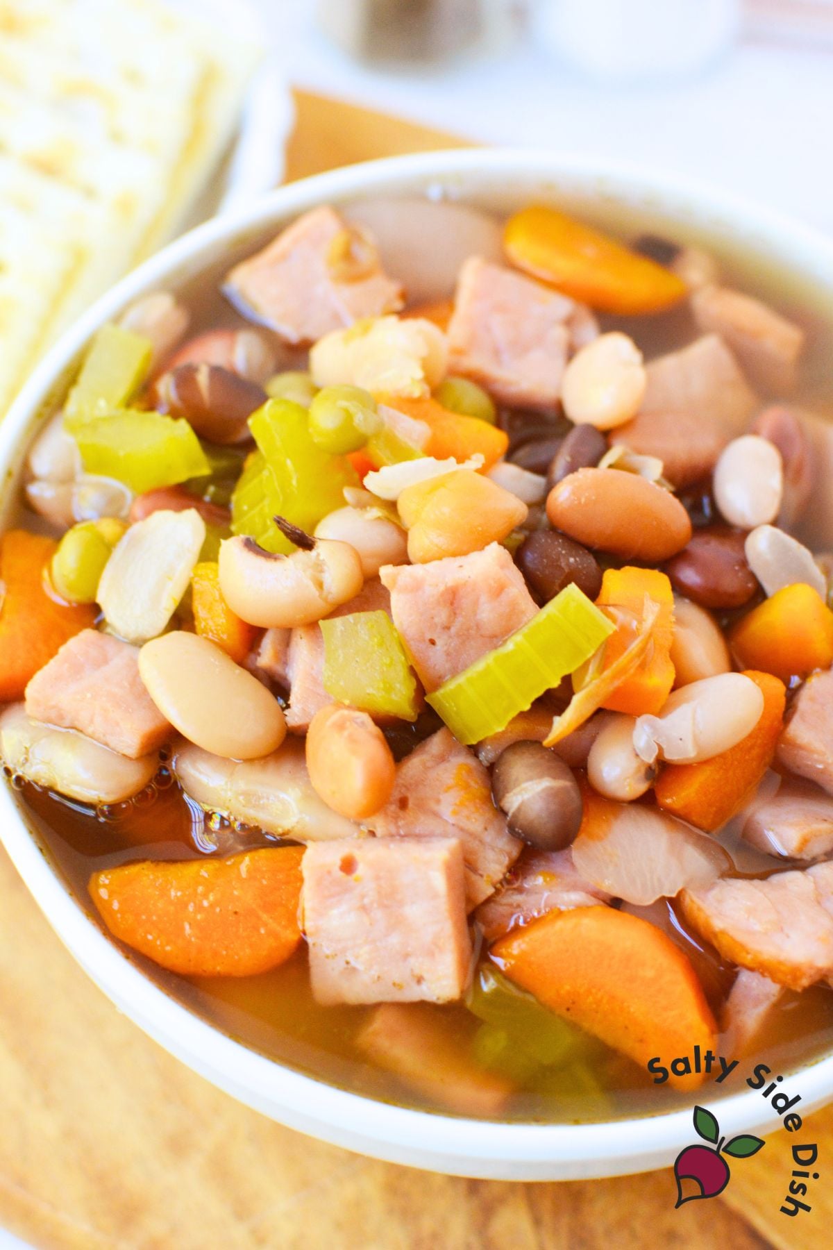 Close-up of hearty ham and bean soup with 16 varieties of beans, chunks of ham, carrots, and celery.