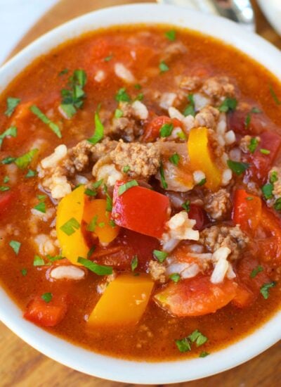 Close-up of stuffed pepper soup with ground beef, red and orange bell peppers, white rice, and tomatoes in a savory broth.