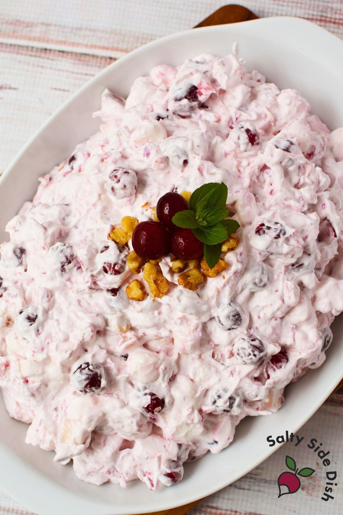 Cranberry salad on a white serving platter garnished with cranberries, walnuts, and mint leaves.