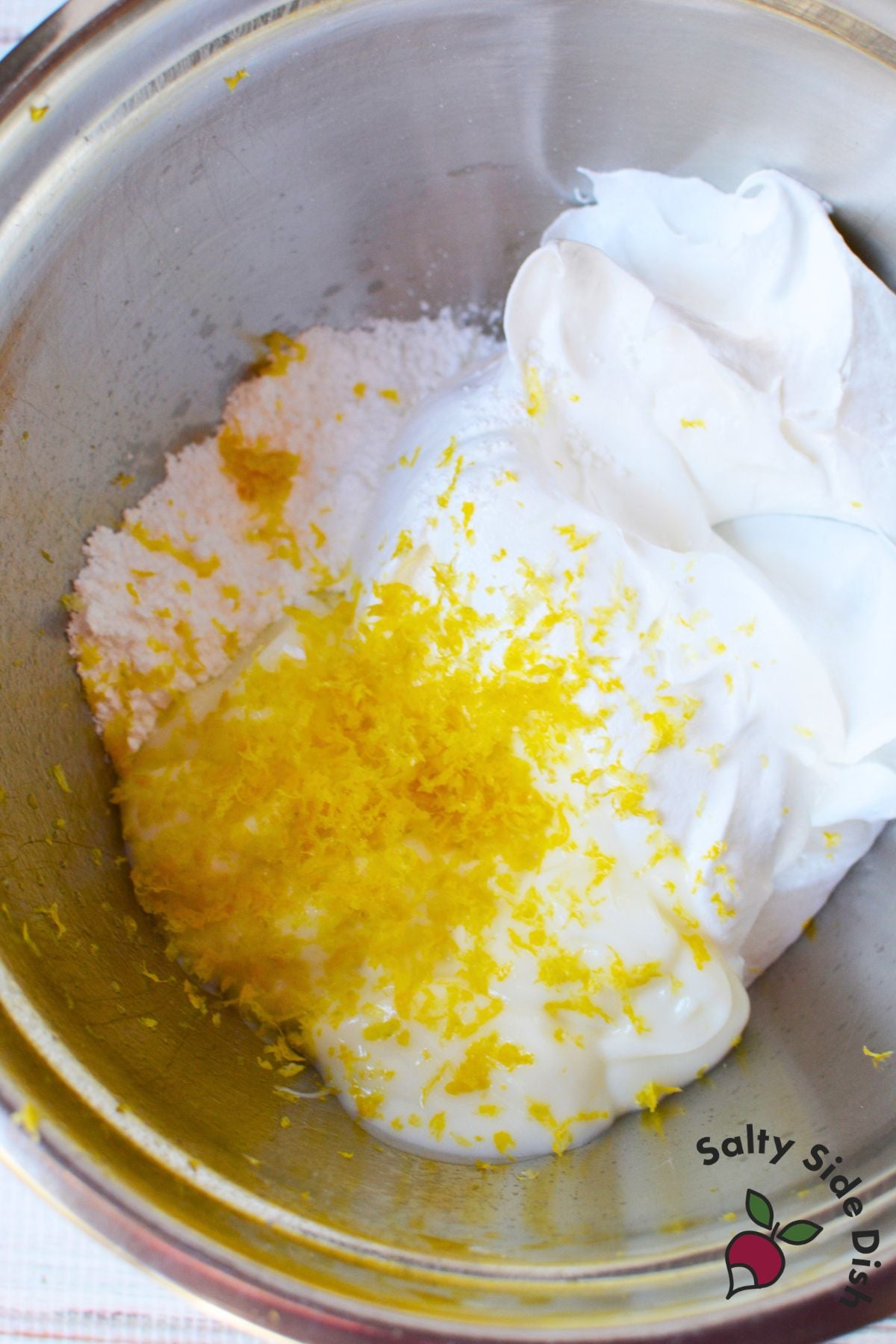 Lemon zest, powdered sugar, vanilla yogurt, and whipped topping combined in a mixing bowl to make lemon fruit dip.