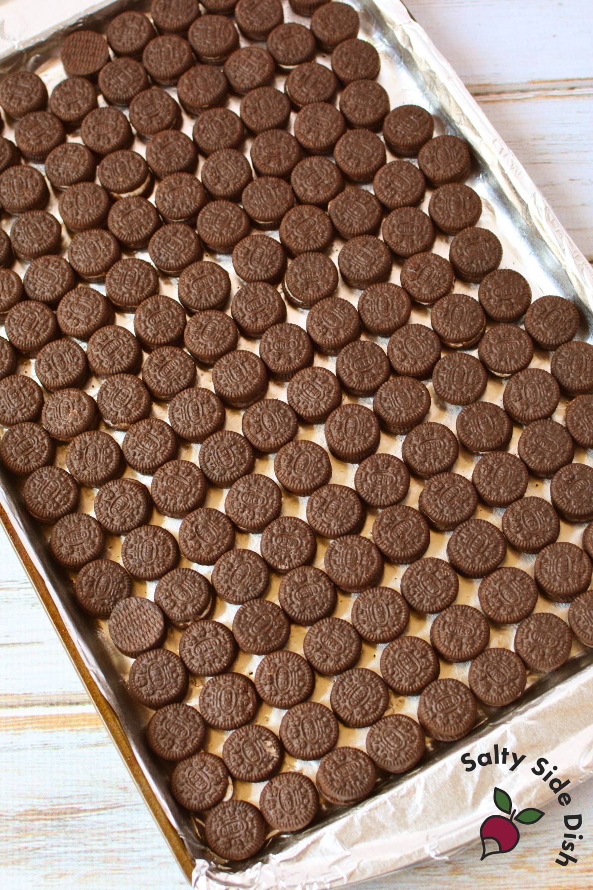 Whole Mini Oreo cookies arranged in a single layer on a foil-lined baking sheet before adding the toffee.
