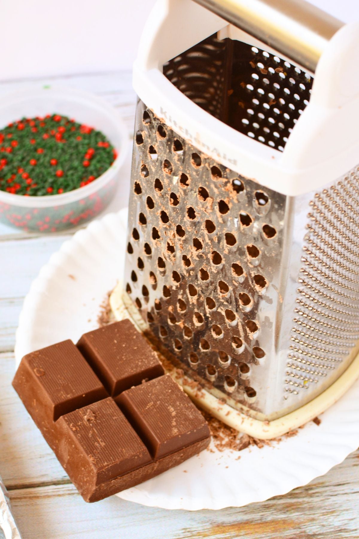 Chocolate almond bark beside a box grater used to prepare the chocolate topping for Mini Oreo toffee.
