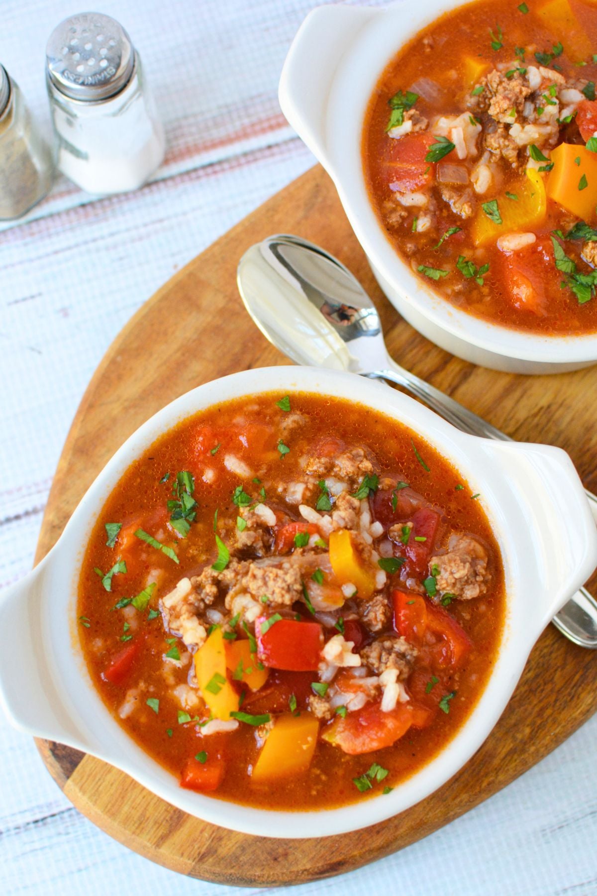 Two bowls of homemade stuffed pepper and rice soup with tender bell peppers, ground beef, tomatoes, and fresh parsley.