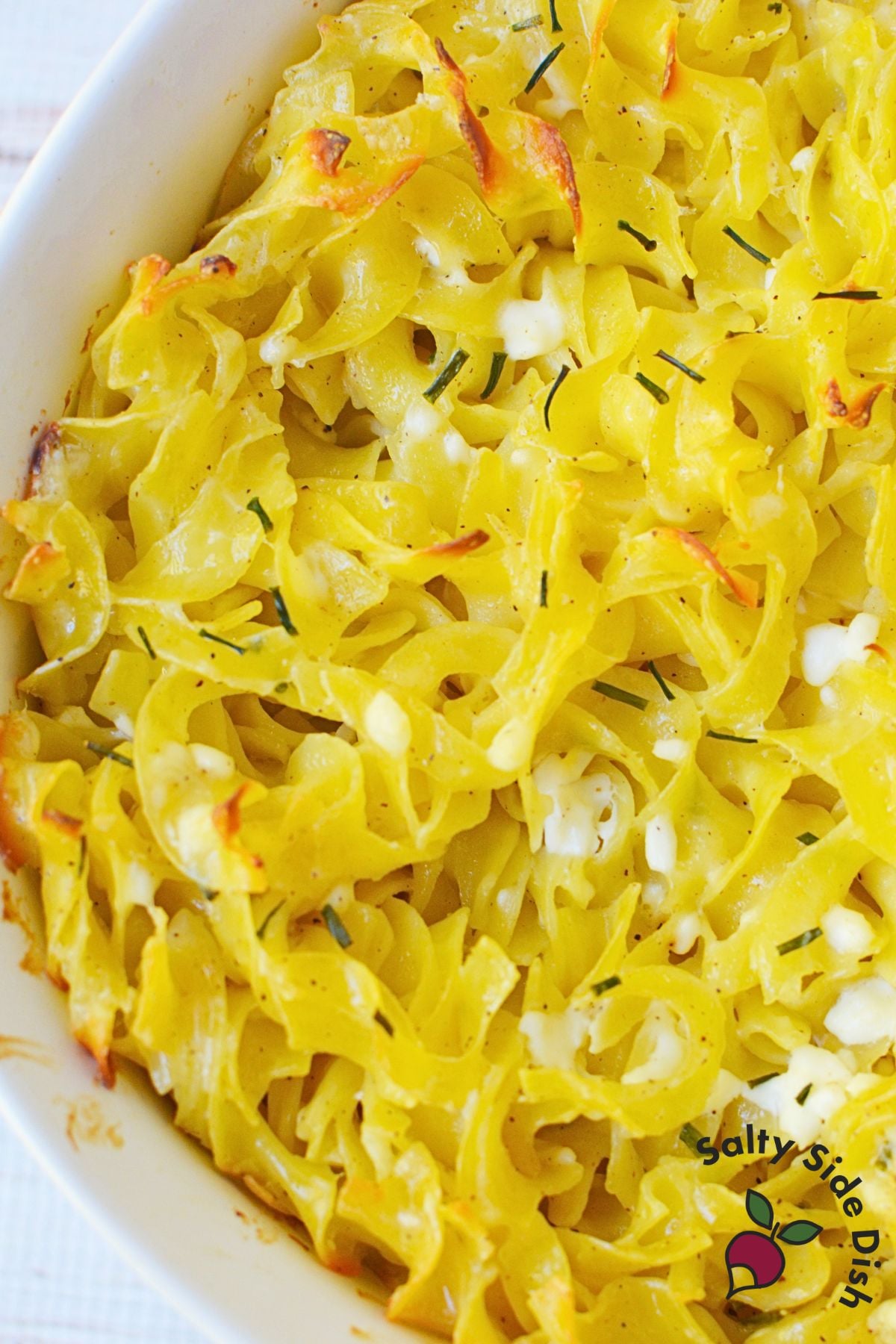 Close-up of baked Casserole Marie Blanche showing lightly crispy egg noodles with cottage cheese and fresh chives.